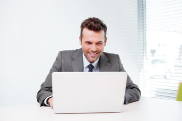 Happy businessman working on laptop in the office