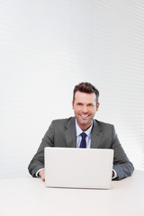 Happy businessman working on laptop in the office