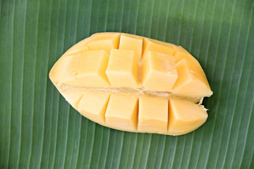 Ripe mango with slices on banana leaves.