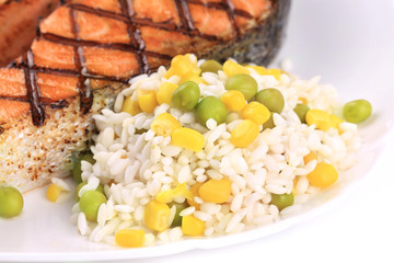 Grilled salmon steak with vegetables on plate.