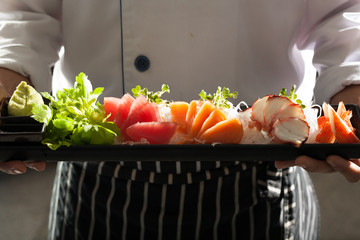sashimi, a chef uniform holding a dish of Japanese Sashimi