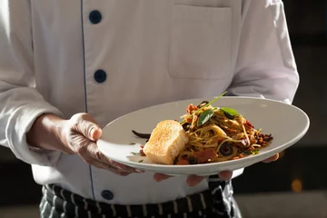 Crédence de cuisine en verre imprimé Plats de repas Spaghetti, a chef uniform holding a dish of seafood spaghetti