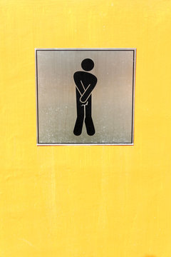 Male toilet sign on yellow wall.
