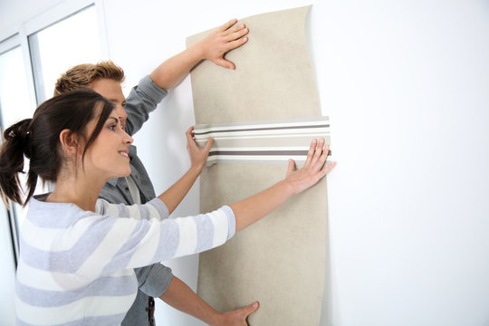 Young couple choosing wallpaper for new home
