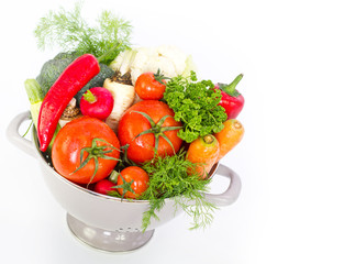 Fresh vegetables in metal colander over white