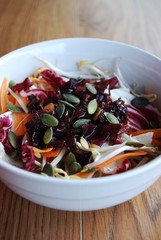Spring salad in white bowl on wooden background