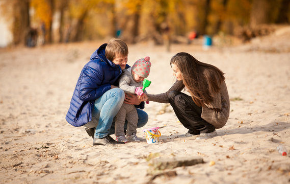 Young Family Playing On Beach With Daughter At Autumn