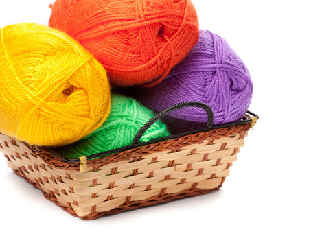 four yarn skeins in yellow, orange, green, purple colors in bask