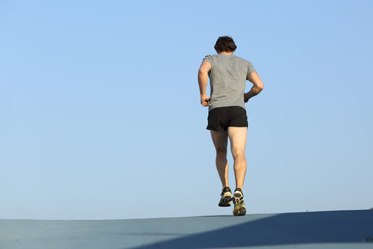 Back View Of A Jogger Man Running Against Blue Sky