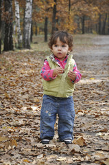 Little girl standing on the road the woods.