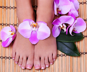 Pedicure with pink orchid flowers on bamboo mat