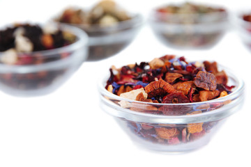 Different kinds of dry tea in bowls isolated on white