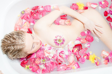 blond woman lying in bath with rose petals