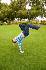 Fototapeta na wymiar Child playing on green grass in a park jumping