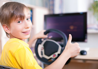 Funny child playing at computer driving showing thumbs up