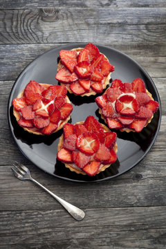 strawberries cakes with pastry cream on plate on wooden table