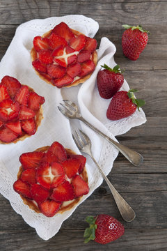 strawberries cakes on white napkin with little forks on table