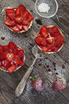 strawberries cakes with cream and icing sugar on rustic table