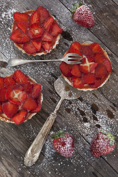 strawberries cakes with pastry cream and icing sugar on table