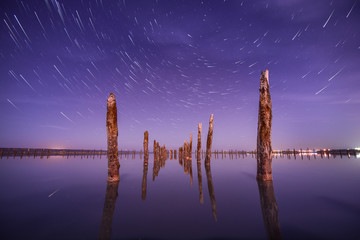 Poles in the water at night on a background star trails - 62813046