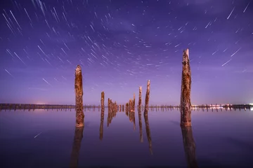 Rolgordijnen Poles in the water at night on a background star trails © Q-lieb-in