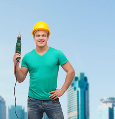 smiling manual worker in helmet with drill machine