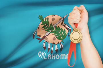 Medal in hand with flag on background - State of Oklahoma.