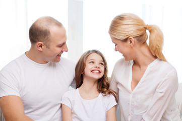 smiling parents and little girl at home