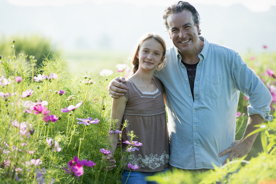 Summer on an organic farm. A man and a girl in a field of flowers.