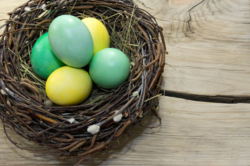 Easter eggs in nest on wooden background