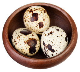 Three quail eggs on a brown plate