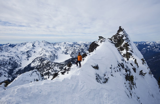 A skier on a ridgeline, pausing before skiing The Slot on Snoqualmie Peak in the Cascades Ranges, Washington state, USA.