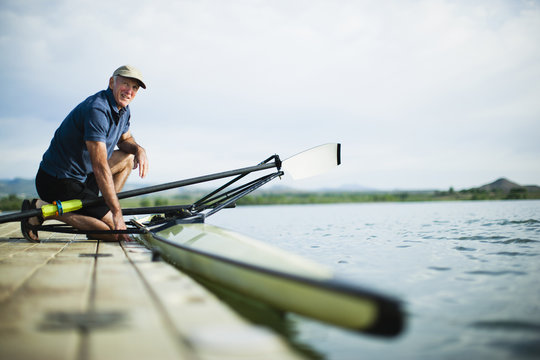 A middle-aged man on a jetty preparing a rowing boat for an outing. 