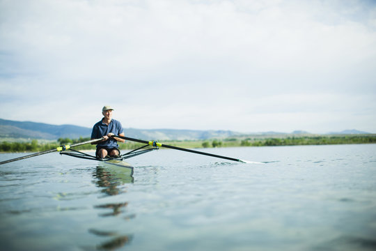 A man in a rowing boat using the oars.