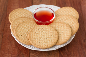 cookies with jam on plate on brown background