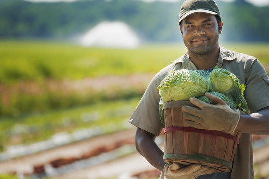 A man holding a basket of freshly harvested vegetables. 