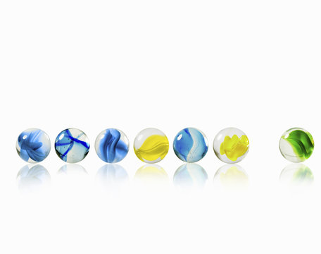 A row of glass marbles of different patterns and colours, with one separated from the rest. 