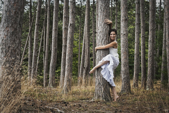 A woman dancing gracefully in the open air beside a tree in the forest. Woodstock, New York State, USA