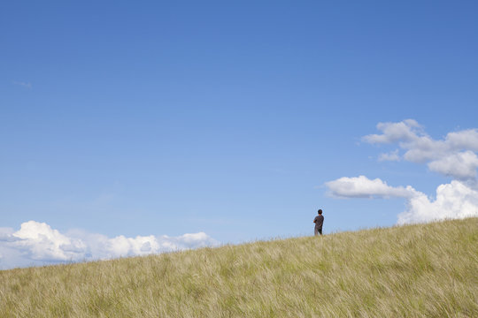 A man standing on the crest of a hill. 