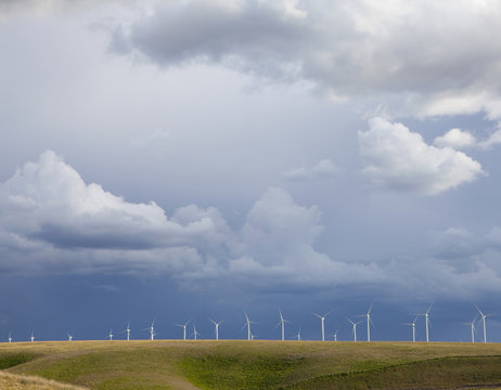 A line of wind turbines on a ridge, against a stormy sky.