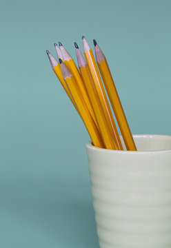 Sharpened pencils in cup, on a blue background. 