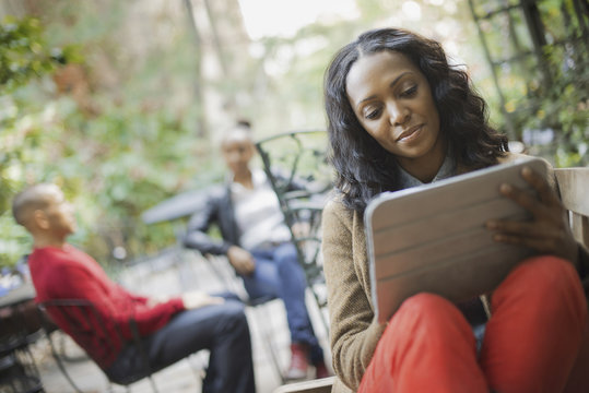 Scenes from urban life in New York City. Outdoors. Two people in background. A woman using a computer tablet or pad.