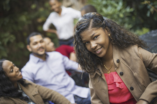 Scenes from urban life in New York City. A group of friends sitting together in a leafy square. Men and women. A teenage girl in the fore.