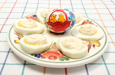 Halves of eggs with mayonnaise and painted egg on colorful plate