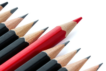 Obraz premium Row of black pencils with one red pencil in middle