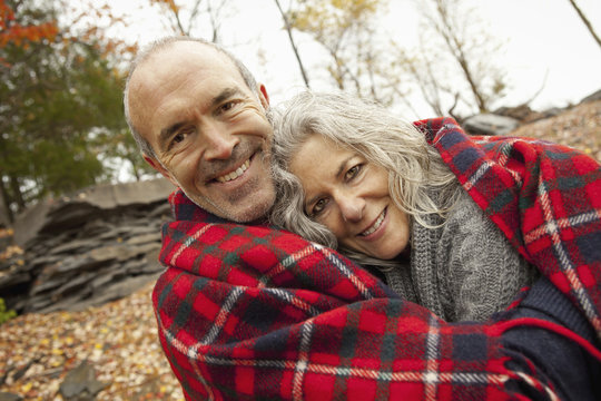 A couple, man and woman on a day out in autumn. Sharing a picnic rug to keep warm.