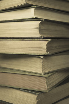 A stack of old hard cover books, with worn edges and aged yellowing paper.
