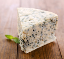 Tasty blue cheese with basil, on wooden table