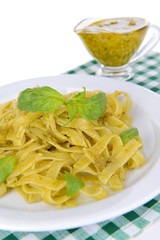 Delicious pasta with pesto on plate on table close-up