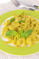 Delicious pasta with pesto on plate on table close-up